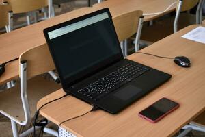 A black laptop and a phone on the desktop. An office workplace with a computer. photo