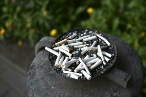 An ashtray for cigarette butts on the street. Smoked cigarettes in the trash. photo