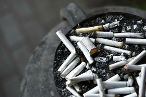 An ashtray for cigarette butts on the street. Smoked cigarettes in the trash. photo