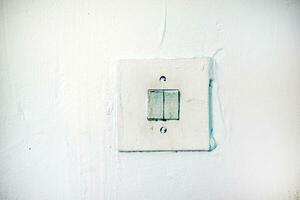 An old light switch on the wall. Electrical switching. Painted switch. photo