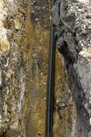 A plastic black gas pipe at the bottom of the trench. A dug trench for laying a gas pipe. photo