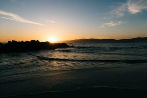 Sunset behind the rocks on the beach photo