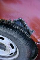 A rotten car. A rotten hole in the car body. A rotten car wing. photo