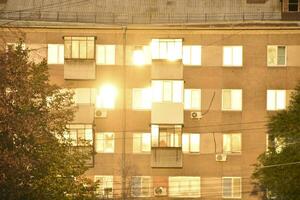 A building in the city is flooded with sunshine and a summer street with cars. Windows in the sun. photo