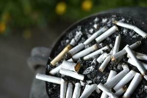 An ashtray for cigarette butts on the street. Smoked cigarettes in the trash. photo