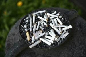 An ashtray for cigarette butts on the street. Smoked cigarettes in the trash. photo