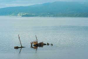 sunken ship against the backdrop of a sea bay with foggy mountains in the background photo
