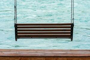 bench-swing over water on the bank of a fast river photo