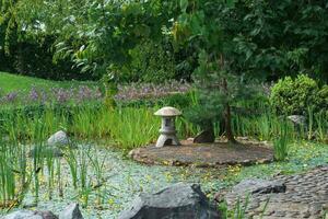 Roca linterna en un pequeño isla en el medio de un estanque en un japonés jardín foto