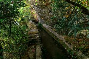 concrete irrigation canal under the rock in a mountainous area photo