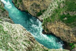 top view of a fast mountain river flowing at the bottom of a deep canyon photo