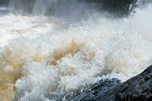 muddy turbulent stream under a rock during high water photo