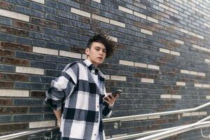 young man with a phone against a brick wall photo