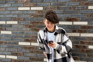 young man reading funny message on phone against a brick wall photo