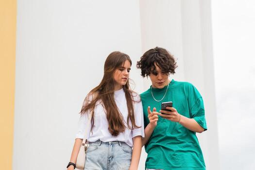 two young people look at the phone, perhaps trying to find their way photo
