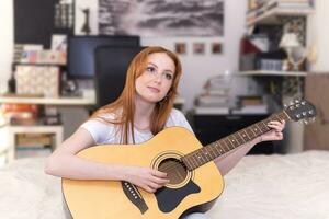 young woman playing acoustic guitar at home photo