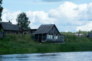 derelict village on the river bank, abandoned wooden houses with empty windows photo