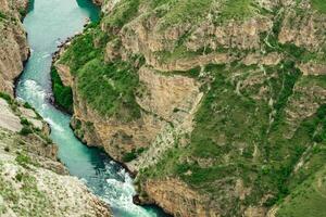 top view of a fast mountain river flowing at the bottom of a deep canyon photo