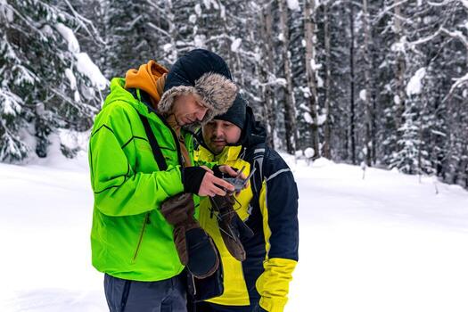 operator with assistant standing in a winter forest and controls an aerial drone photo