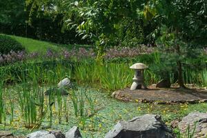 Roca linterna en un pequeño isla en el medio de un estanque en un japonés jardín foto