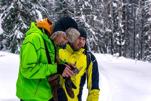 operator with assistant standing in a winter forest and controls an aerial drone photo