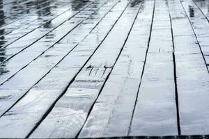 mojado tableros de un de madera acera durante el lluvia foto