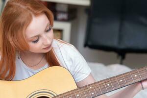 young woman playing acoustic guitar at home photo