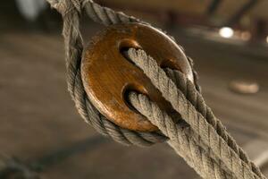detail of the rigging of an old sailing ship, a wooden triple deadeye block with lanyard photo