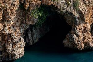 sea cave in the rocks above the water photo