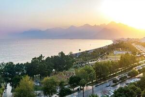 sunset view of Konyaalti beach from nearby rocks in Antalya, Turkey. Beydaglari mountains in fog are visible in the background. photo