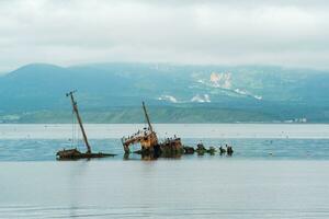 sunken ship against the backdrop of a sea bay with foggy mountains in the background photo