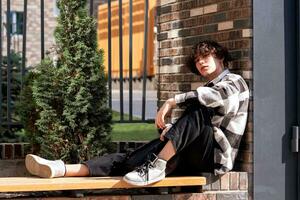 young man sits relaxed on a city bench photo