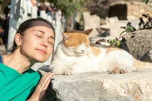 girl posing next to a dozing cat, imitating his facial expression photo