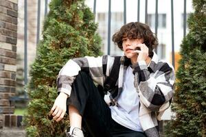 young man talking on the phone while sitting on a bench in the city photo