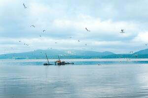 sunken ship against the backdrop of a sea bay with foggy mountains in the background photo