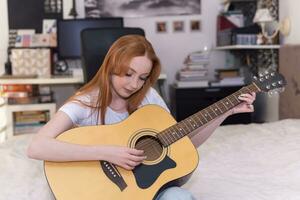 young woman playing acoustic guitar at home photo