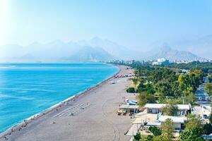 view of Konyaalti beach from nearby rocks in Antalya, Turkey. Beydaglari mountains in fog are visible in the background. photo