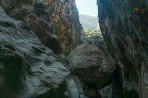 huge stone hangs stuck between two rocky walls of the Goynuk canyon in Turkey photo