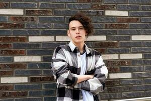 young man with a phone against a brick wall photo