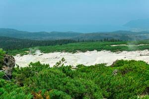 fumarole field on the slope of Mendeleev volcano on Kunashir island overlooking the ocean in the haze photo