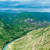 montaña paisaje en el Cáucaso en daguestán, ver de el cañón de el sulak río con el pueblo de antiguo zubutli en el distancia en el pendiente, visible altísimo buitre foto