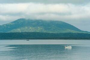 sea bay with foggy mountains in the background, view of the Mendeleev volcano on a cloudy day photo