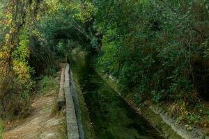 concrete irrigation canal among vegetation in a mountainous area photo