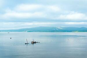 remains of a sunken ship against the backdrop of a sea bay with foggy mountains in the background photo