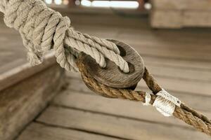 detail of the rigging of an old sailing ship, a wooden triple deadeye block with lanyard photo