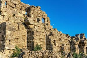 ruins of ancient city walls against the backdrop of the sky with moon in Side, Turkey photo