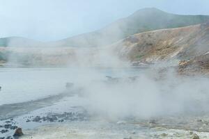 steaming hydrothermal outlet on the shore of the hot lake in the caldera of the Golovnin volcano on the island of Kunashir photo