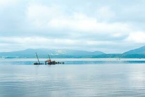 remains of a sunken ship against the backdrop of a sea bay with foggy mountains in the background photo