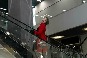 smiling young woman going up the escalator in the office center or mall photo