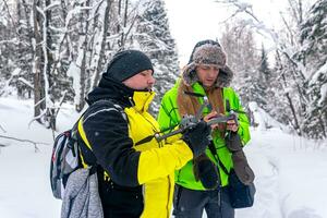 two men in the winter forest launch a quadcopter photo